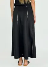 Pollera larga de lino color blanco, con corte acampanado y paneles verticales con costuras a la vista.