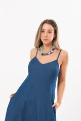 Vestido largo de denim fino y liviano, color azul, con breteles finos, escote en V y falda amplia con recortes verticales y bolsillos laterales.