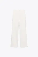 Pantalón blanco de tiro alto, corte ancho tipo flare, con cierre frontal de cremallera y gancho metálico.