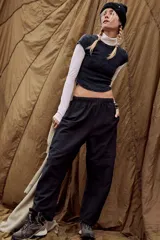 Pantalón deportivo negro de tiro alto, con silueta relajada y corte ajustado hacia el tobillo. Presenta costuras definidas y piernas ligeramente curvadas.