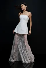 Vestido largo blanco con diseño strapless, cuerpo estructurado con frunces en el busto y falda larga de encaje transparente con diseño floral.