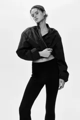 Leggings negros de tiro alto en punto elástico, con pliegues frontales pespunteados y estribos en los tobillos.