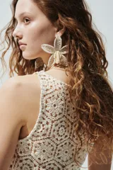 Vestido corto de crochet color beige, sin mangas, con escote redondo y diseño ligeramente acampanado en el bajo.