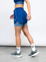 Short deportivo Umbro de color azul con calza interna incorporada. Cuenta con cintura elástica con cordón de ajuste, ribete reflectante y logo de la marca estampado en la pierna.