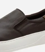 Championes tipo slip-on de cuero marrón con detalle de talón en tono contrastante y suela de goma blanca.