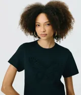 Remera negra de algodón con cuello redondo, manga corta y bordado frontal en relieve con forma de mariposa.