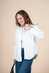 Camisa blanca de corte clásico con bolsillo en el pecho, mangas largas y botones al tono.