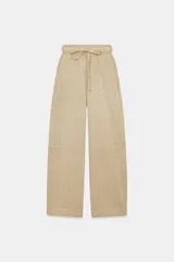 Pantalón balloon de tiro alto color beige, confeccionado en algodón, con cintura elástica ajustable mediante cordones y bolsillos delanteros.