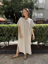 Vestido largo de tejido de punto con diseño de rayas verticales en blanco y negro. Presenta escote en V, mangas cortas y tajos laterales en el ruedo para mayor movimiento.