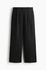 Pantalón sastrero de corte holgado color negro, con piernas amplias, pinzas frontales, pliegues marcados y trabillas para cinturón.
