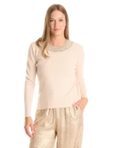 Buzo de tejido fino color beige, con cuello redondo decorado con apliques de brillos y mangas largas.