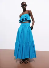 Top corto tipo palabra de honor, con diseño de volantes en capas y cierre de cremallera en la parte posterior.