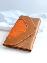 Billetera de cuero color naranja y marrón con cierre de broche y monedero externo.