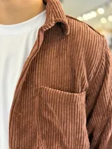 Sobrecamisa de pana color marrón chocolate, de manga larga, con cuello camisero, cierre frontal con botones y un bolsillo aplicado en el pecho.