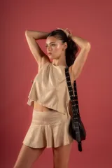 Blusa color beige con cuello halter, abierta a los costados y atada.