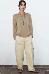 Jeans de tiro medio con diseño cargo, bolsillos de plastrón y pernera holgada que se estrecha hacia el tobillo. Cierre frontal con cremallera y botón.