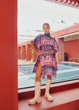Poncho tejido con cuello alto y aberturas laterales, con diseño geométrico multicolor en tonos rosa, azul y violeta.