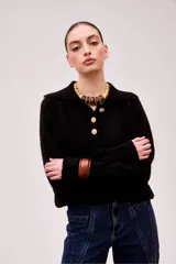 Sweater negro de alpaca con cuello polo, manga larga y cierre frontal con tres botones dorados.