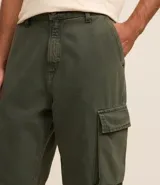 Pantalón baggy color verde militar, confeccionado en sarga de algodón, con cintura con trabillas, cierre con botón y cremallera, y bolsillos cargo laterales. Modelo holgado de estilo vintage.