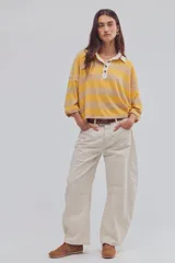 Remera tipo polo de algodón, de calce oversize, con diseño a rayas en tonos azul y celeste, cuello clásico blanco, botonadura corta, hombros caídos y mangas cortas.