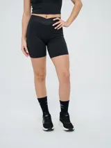 Biker deportiva Umbro para mujer, de color negro, confeccionada con tejido elástico y pretina cruzada con elástico personalizado de la marca.