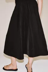 Falda midi de tiro medio color negro, con cintura elástica, bolsillos laterales ocultos y bajo con acabado en línea evasé.
