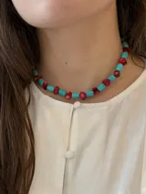 Collar choker hecho a mano con cuentas cilíndricas de turquesa reconstituida y pequeños corales rojos intercalados, con cierre ajustable de acero dorado.