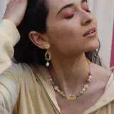 Collar de cuentas de colores pastel con dijes de formas abstractas y perlas de río.