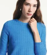 Blusa de punto color celeste con textura ondulada, cuello redondo y mangas largas.