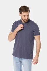 Remera polo de piqué en color azul con estampado de mini print geométrico en toda la prenda. Presenta cuello clásico, cierre frontal con botones personalizados y logo bordado en el pecho.