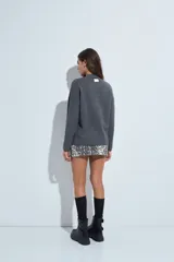 Sweater de punto gris con cuello a la base y diseño de trama geométrica en relieve. Presenta un calce relajado con mangas largas y puños tejidos.