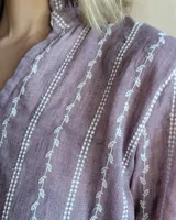 Blusa de algodón con cuello mao y volados, mangas largas con puños elásticos y corte holgado.