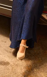 Sandalias de gamuza color beige con punta fina reforzada con detalle metálico, taco cuadrado y pulsera ajustable al tobillo.