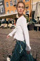 Top de manga larga con textura nido de abeja, escote en pico con detalle de volantes y cierre frontal mediante lazos ajustables.