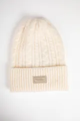 Gorro de lana tejido en ochos con vuelta acanalada y parche frontal con logo de la marca Daniel Cassin.