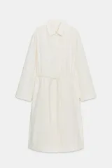 Gabardina oversize color blanco roto, con cuello solapa, manga larga y bolsillos laterales ocultos. Presenta cintura ajustable con cordones a tono y forro interior.