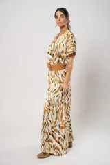 Vestido largo con estampado animal print en tonos camel, blanco y negro. Tiene escote en V, mangas cortas tipo murciélago y tajo frontal. Incluye cinturón ancho de cuero color camel.