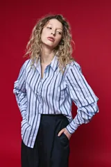 Camisa de algodón celeste con rayas verticales azul marino y marrón, cuello camisero clásico y cierre frontal de botones nacarados.