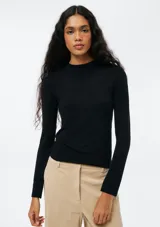 Blusa de manga larga, corte ajustado y cuello alto, confeccionada en tejido de punto negro.