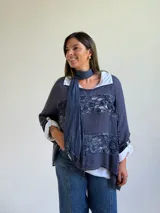 Sweater de punto azul con diseño holgado, que incorpora paneles de encaje floral en el frente y los laterales. Presenta un estilo superpuesto con cuello redondo y mangas largas con puños vueltos.