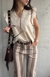 Musculosa de color beige con escote en V, mangas con volados y delicados bordados frontales.