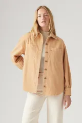 Camisa color beige de pana con corte recto, cuello camisero, cierre con botones a tono, dos bolsillos frontales con solapa abotonada y mangas largas con puños abotonados.