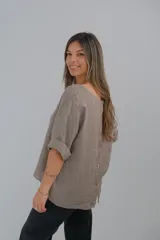 Blusa de lino color visón, de corte holgado, con cuello redondo y mangas cortas con dobladillo.