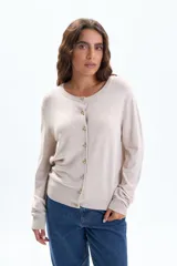 Saco de punto básico color beige, con cuello redondo, manga larga y cierre frontal con botones dorados.