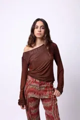 Top de manga larga confeccionado en tejido de tul semitransparente color marrón, con diseño de escote asimétrico que deja un hombro al descubierto.