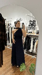 Vestido largo de fiesta color azul oscuro con acabado brillante, diseño de un solo hombro con detalle de cuello tipo choker y falda amplia con caída fluida.