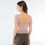 Camiseta de encaje color rosa con textura de puntos, corte ajustado, cuello redondo y mangas cortas con terminación ondulada.