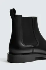 Bota tipo Chelsea de piel lisa color negro, con elásticos laterales para facilitar el calce, plantilla interior de piel, horma redonda y suela con ligero tacón.