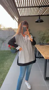 Chaleco de punto gris con ribete negro, escote en V y corte holgado.