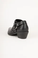 Botineta negra de cuero sintético con punta fina, taco bajo y apliques metálicos.